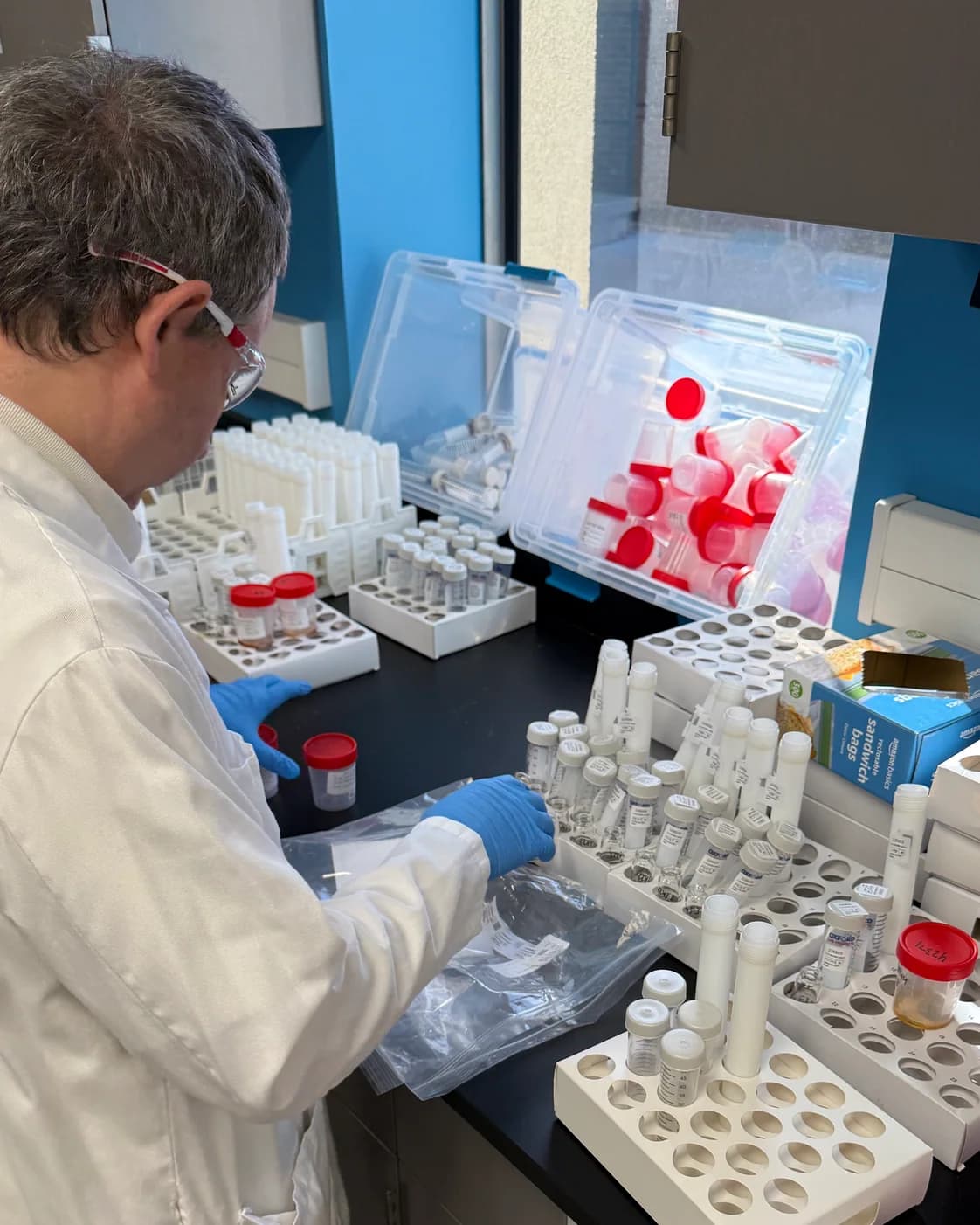 An analyst working through racks of sample tubes at the bench