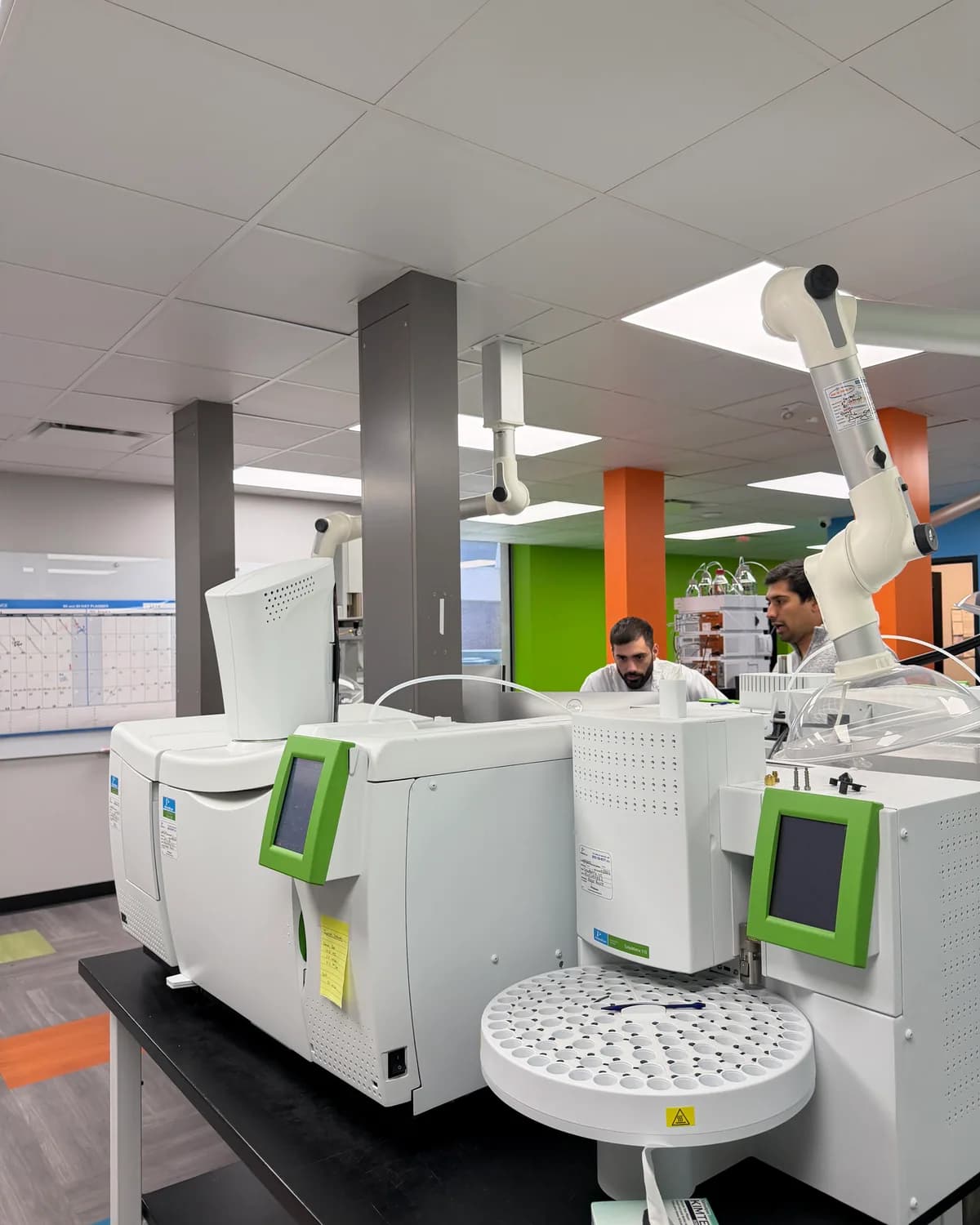 A row of mass spectrometers with analysts working behind them
